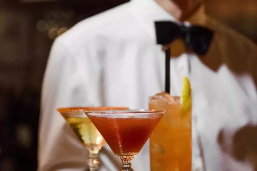 贝博体彩app的abxant餐厅，一个戴着领结的服务器正在赠送鸡尾酒托盘.