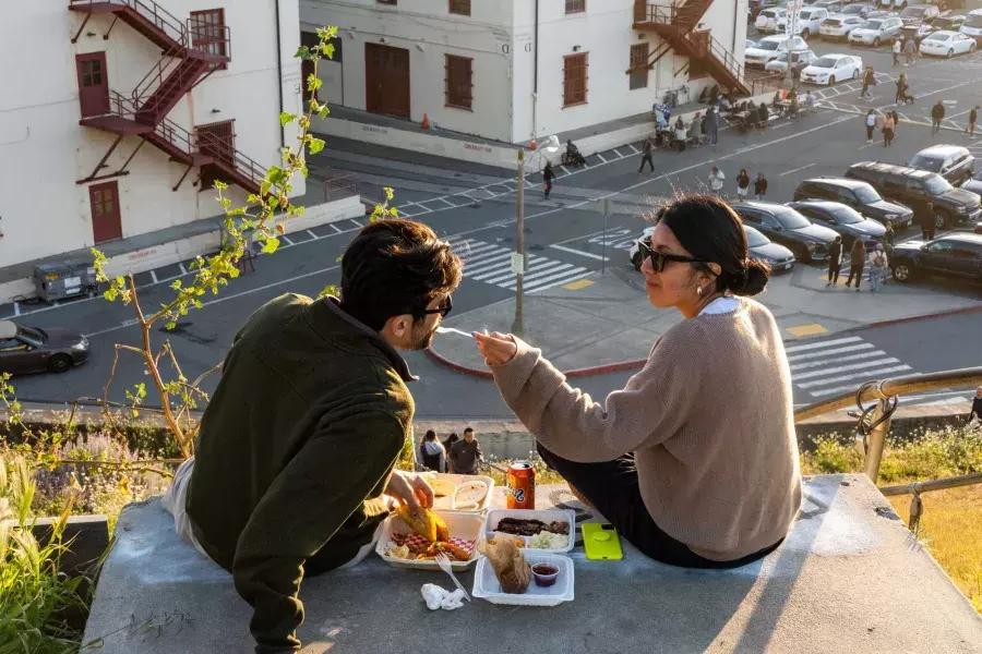 一对情侣在贝博体彩app梅森堡中心的室外用餐。。女性赋予同伴食物的味道。。