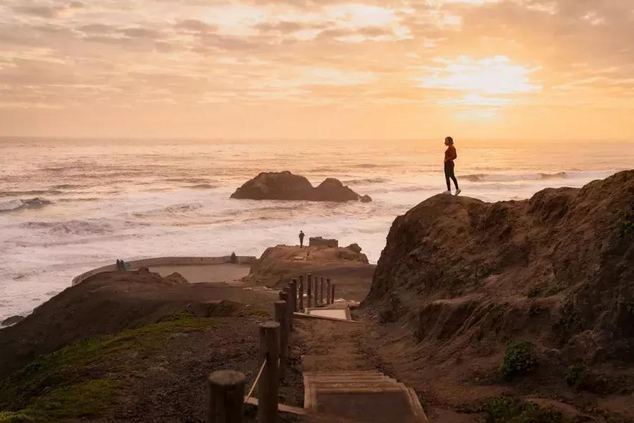 Two people stand on rocks overlooking the ocean at Sutro Baths in 贝博体彩app.
