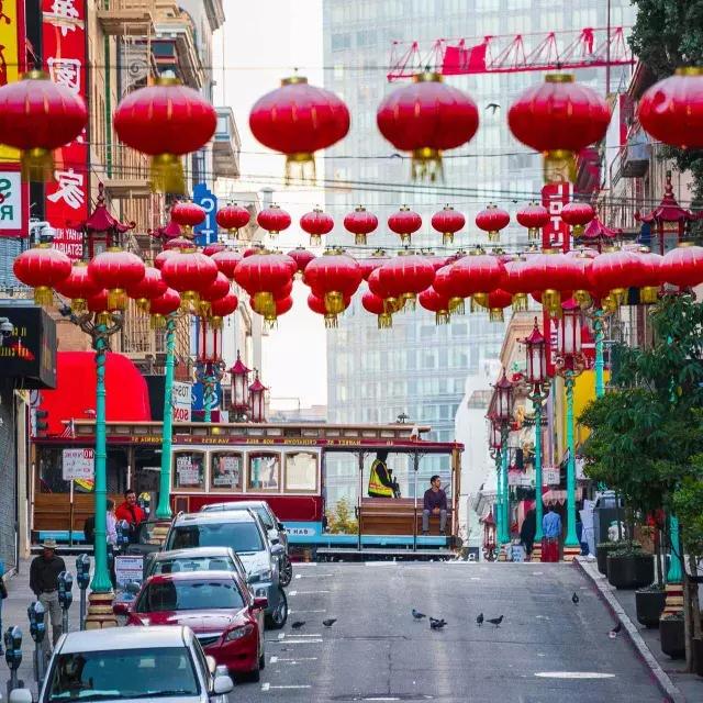 A hilly street 在贝博体彩app's 唐人街 is pictured with red lanterns dangling and a streetcar passing by.
